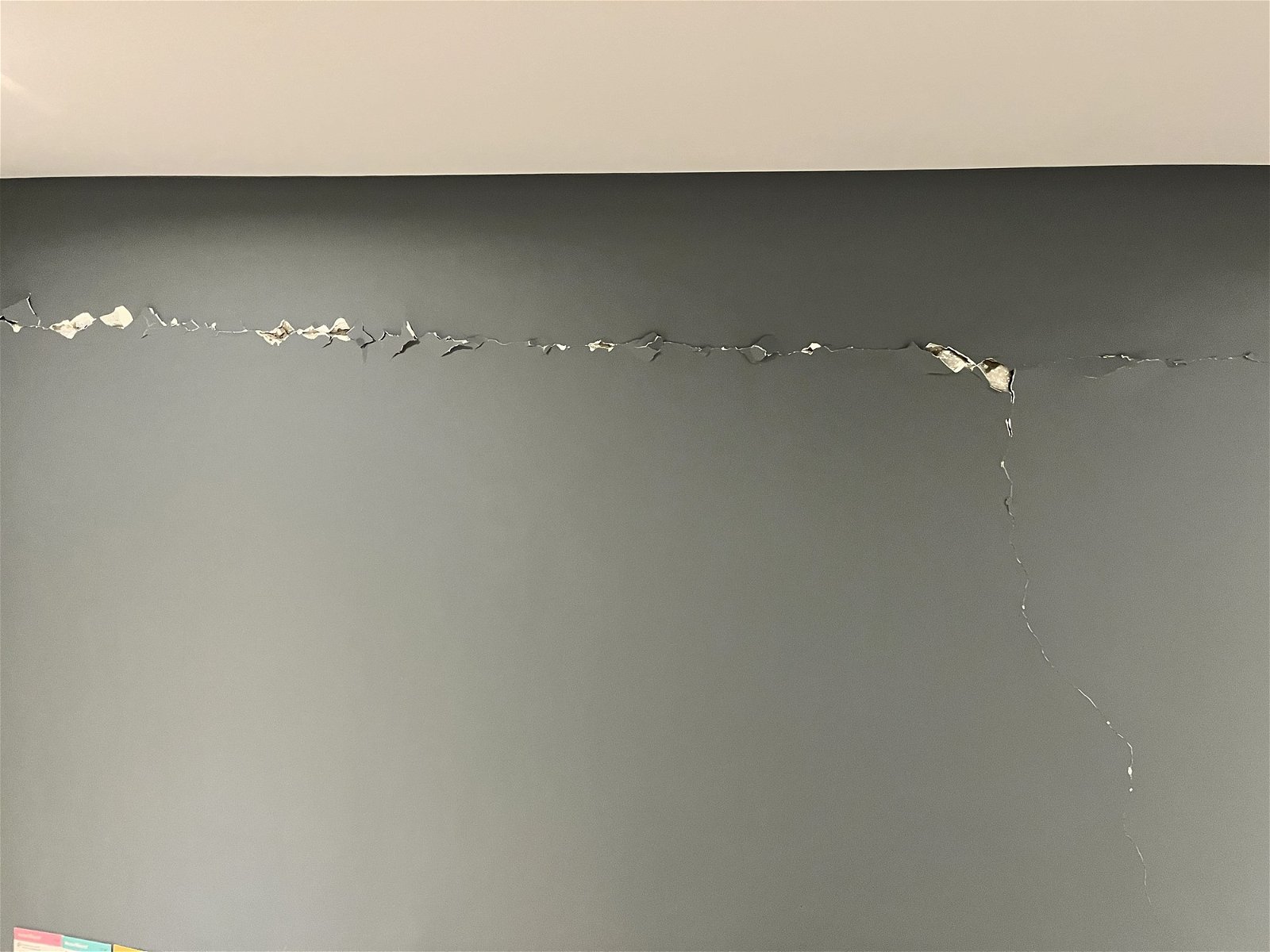 A large crack in a grey wall.