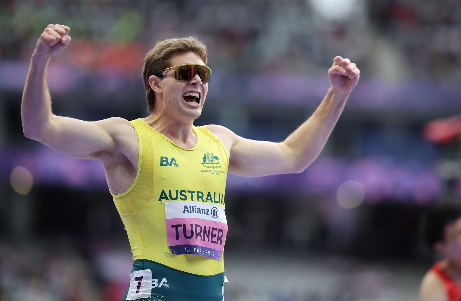 Australian Paralympic runner James Turner has both arms raised in the air with fists as he yells with joy.