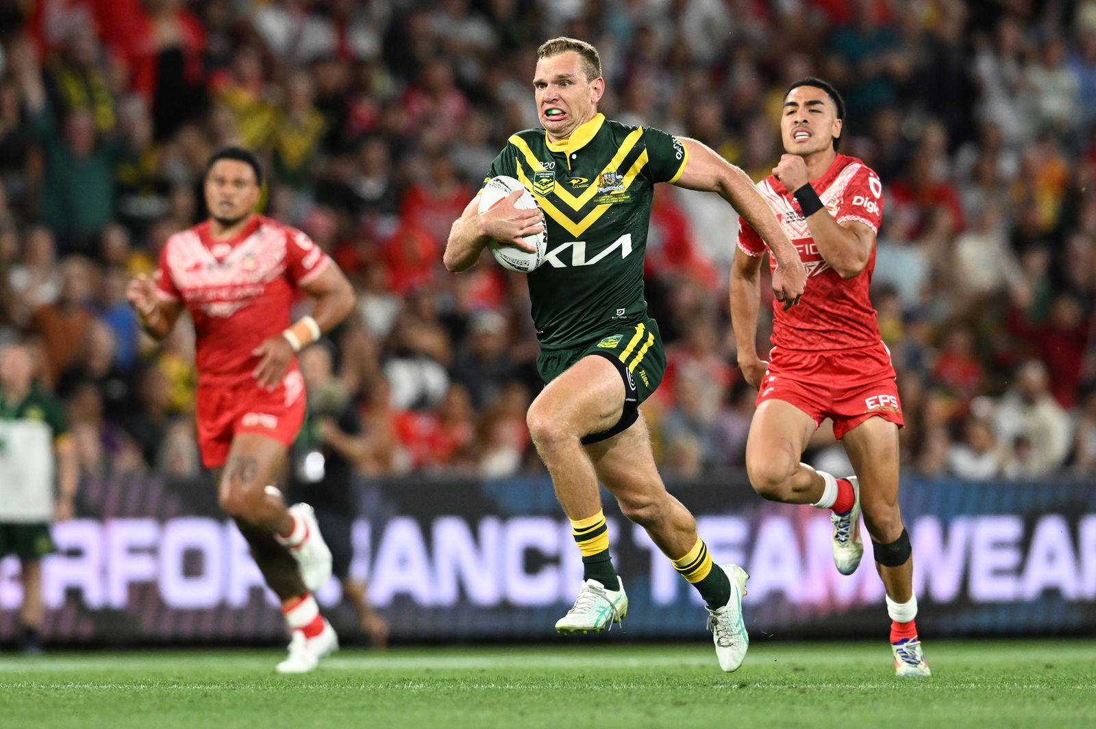 Tom Trbojevic runs with the football as Tongan players chase him.