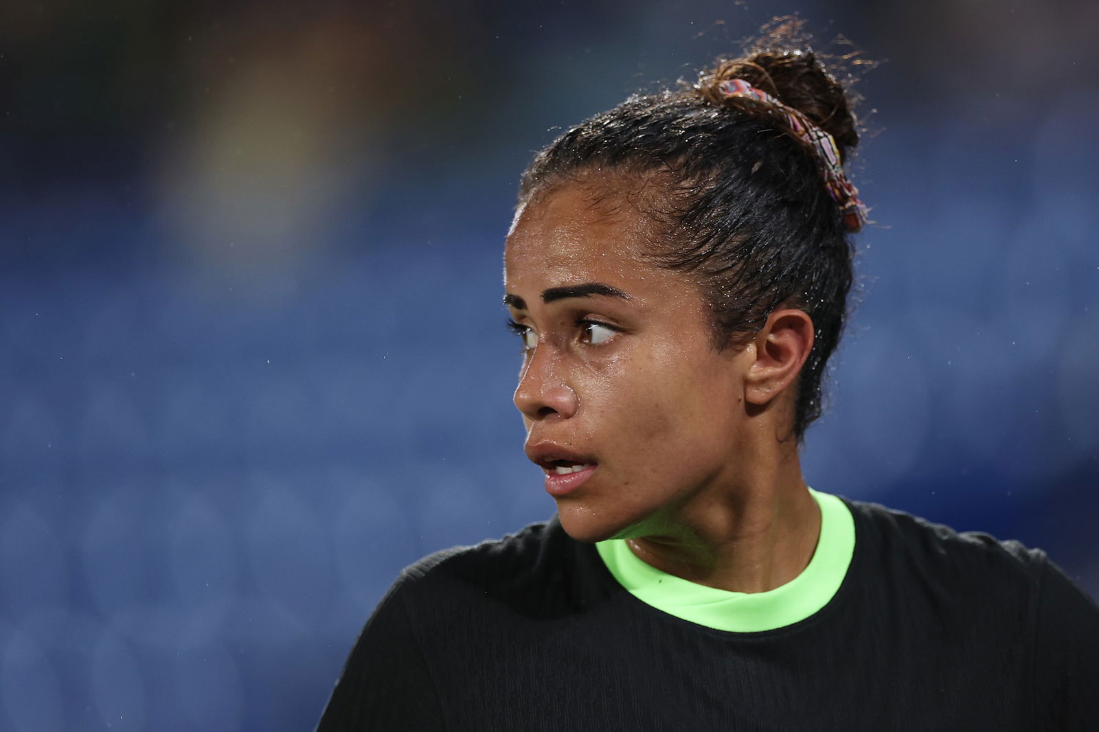 Captura aproximada de uma mulher com cabelo castanho preso para trás e uma camisa de futebol verde