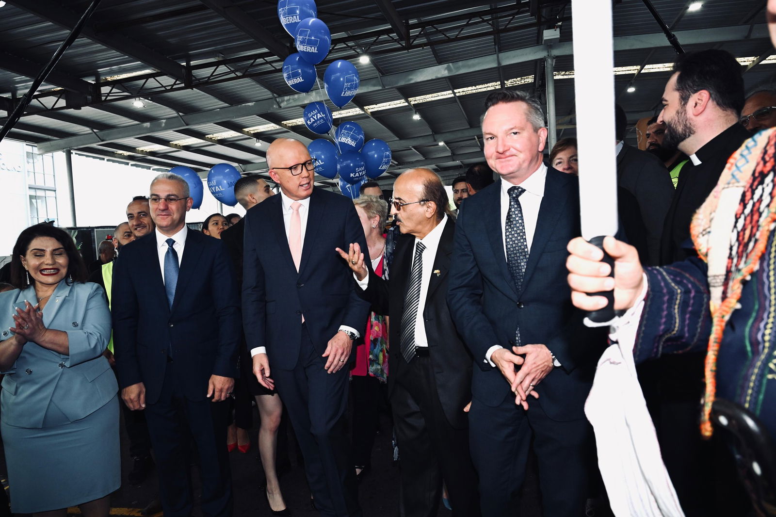 Peter Dutton, Chris Bowen and Assyrian community members speak under a pavilion.