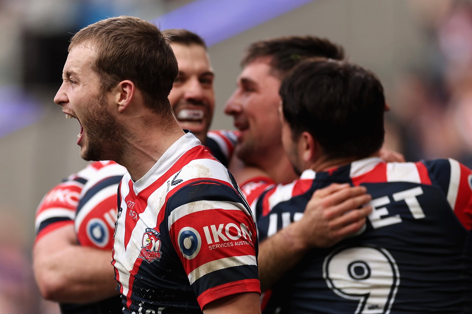 Sam Walker shouts as Sydney Roosters teammates celebrate a try in the background.