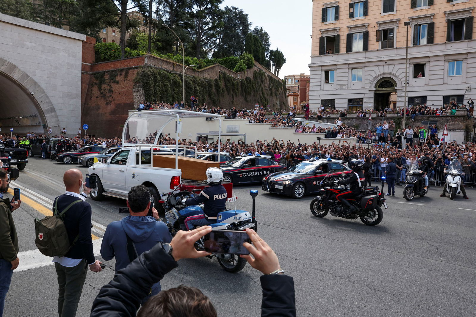 A white hearse is followed by police vehicles.