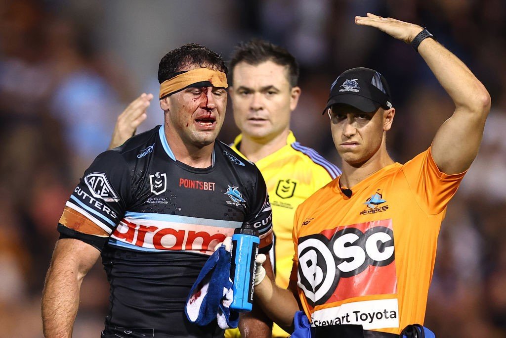 A trainer signals by tapping his head as Dale Finucane is bloodied during an NRL game.