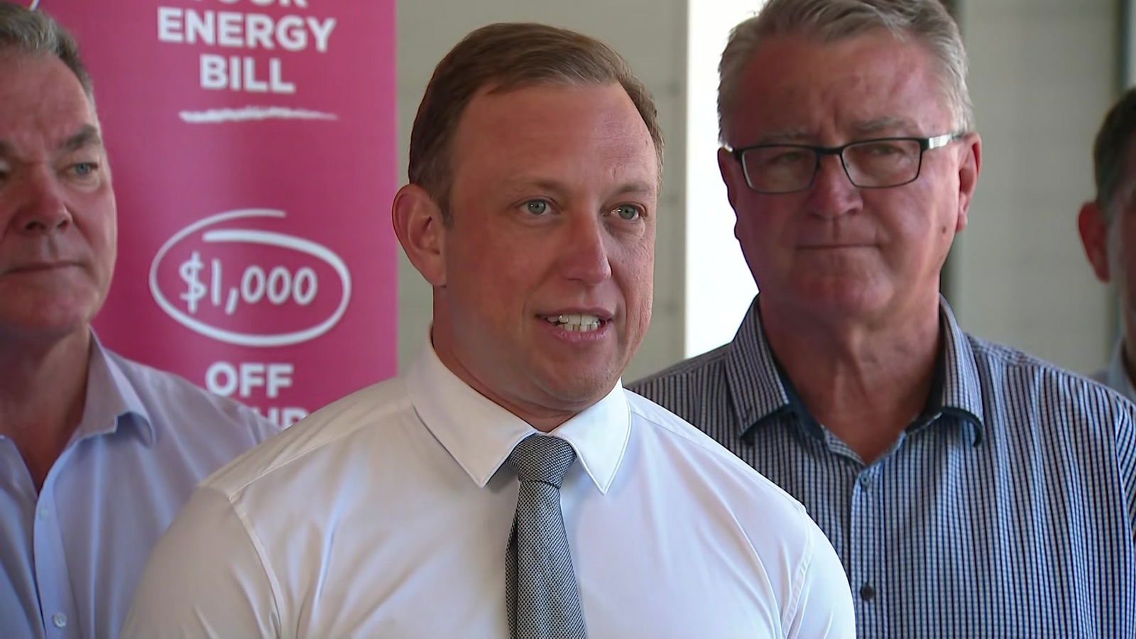 A man in a white shirt and tie speaks.