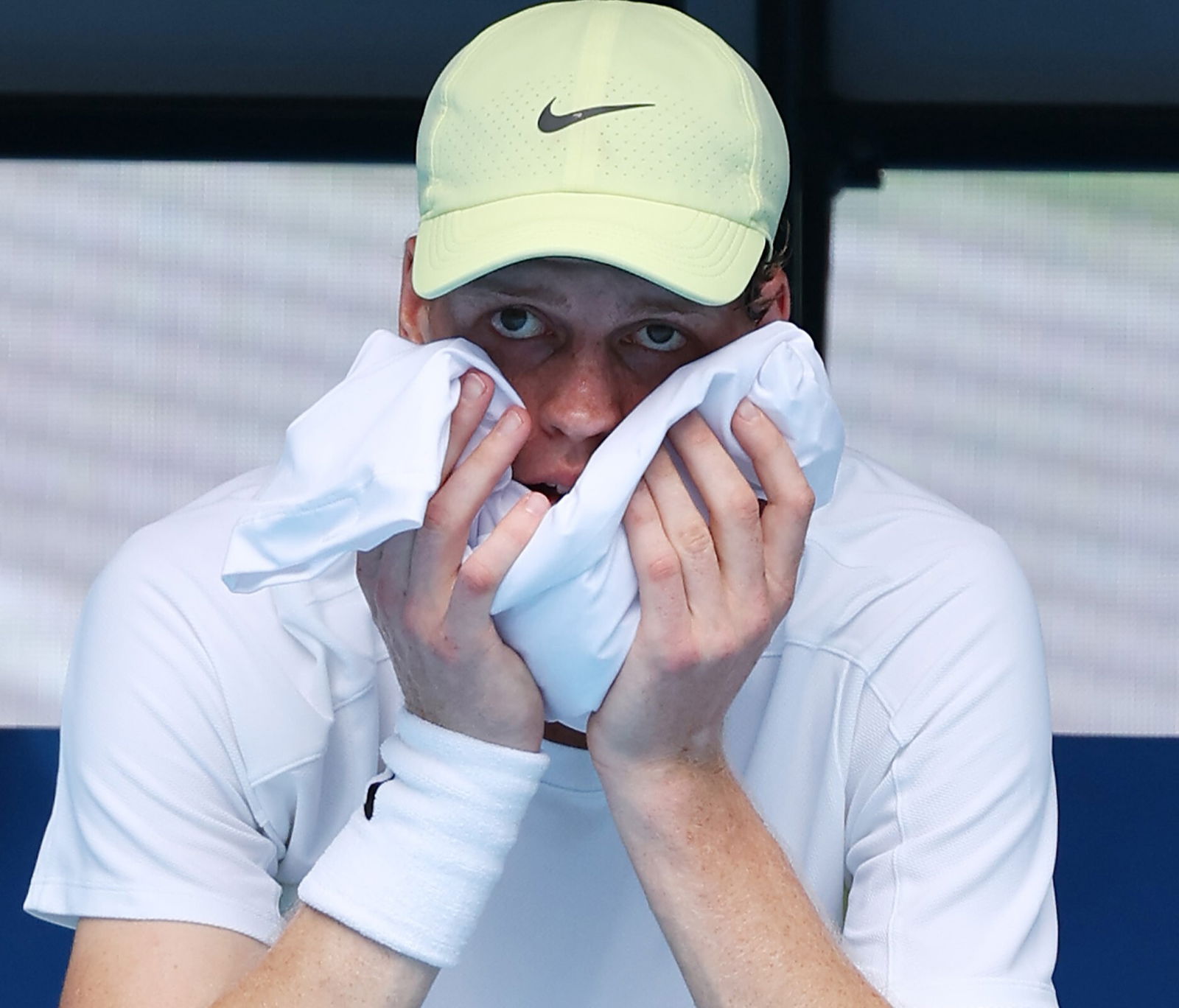 Jannik Sinner with a towel around his face.