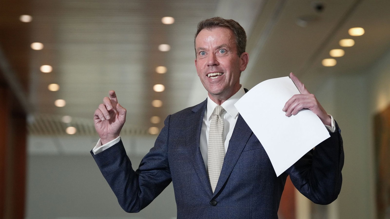Dan Tehan speaks to the media while holding a piece of paper.