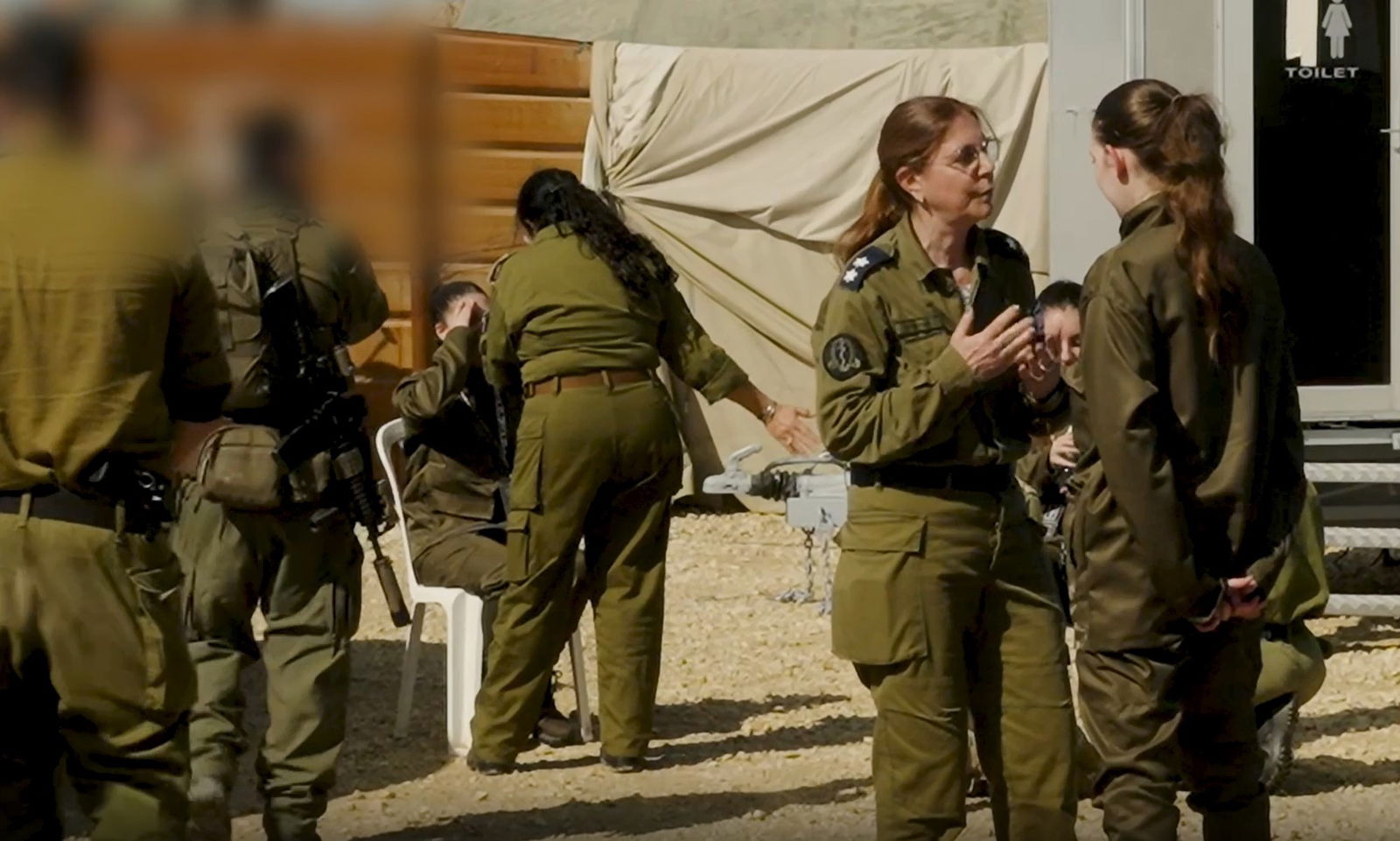 Several soldiers speaking to women.