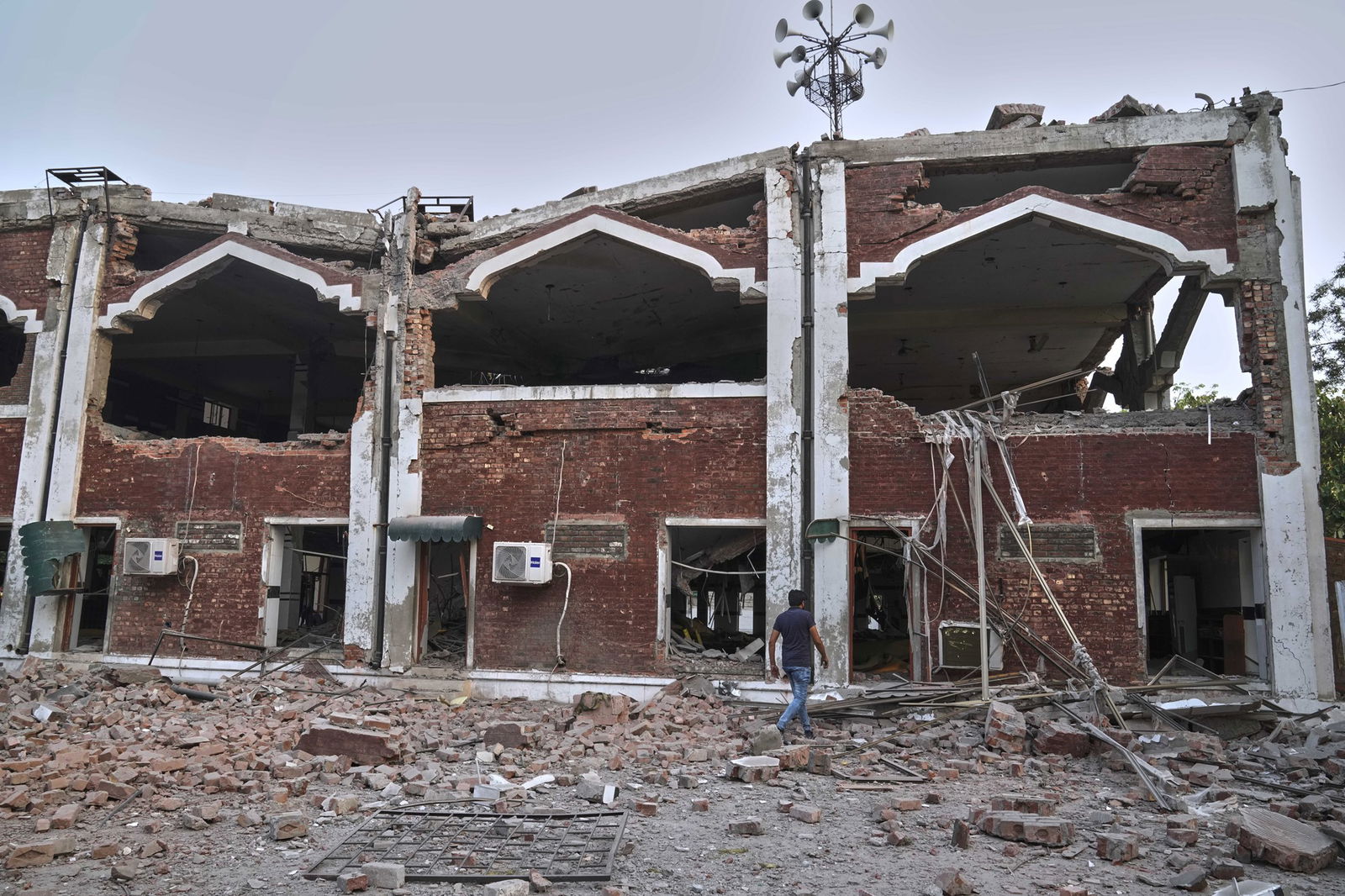 A red-brick two-storey building sits destroyed with bricks strewn at its base