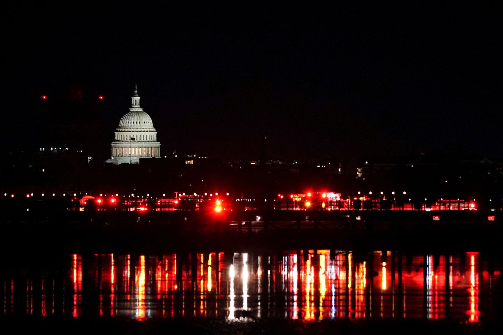 A wide shot of Washington DC with red lights of emergency crews flashing on the river