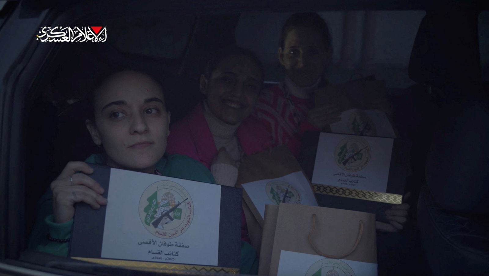 Three women hold brown bags with arabic writing on them. 