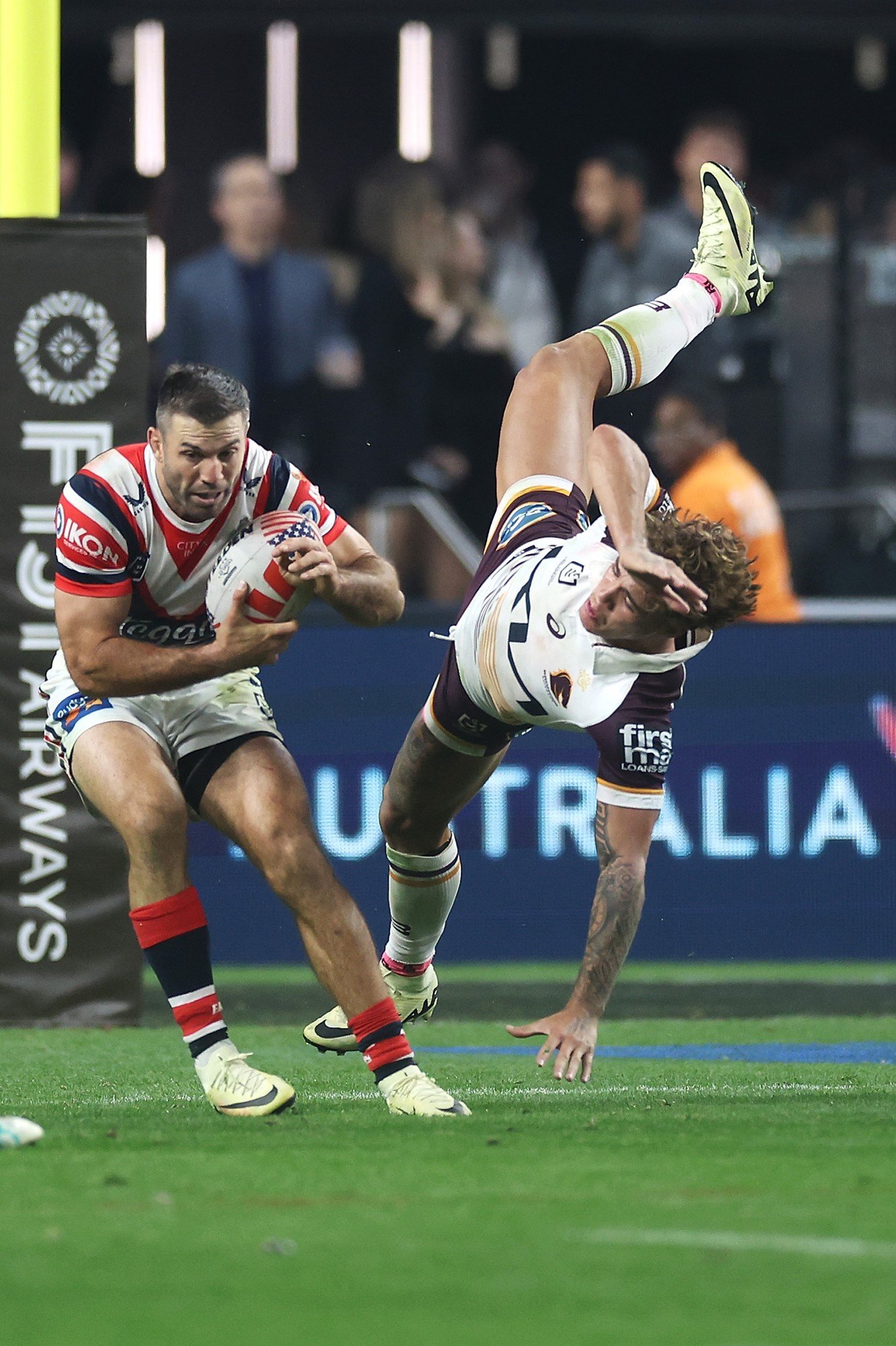 Sydney Roosters fullback James Tedesco with the ball sends Brisbane Broncos fullback Reece Walsh flying.