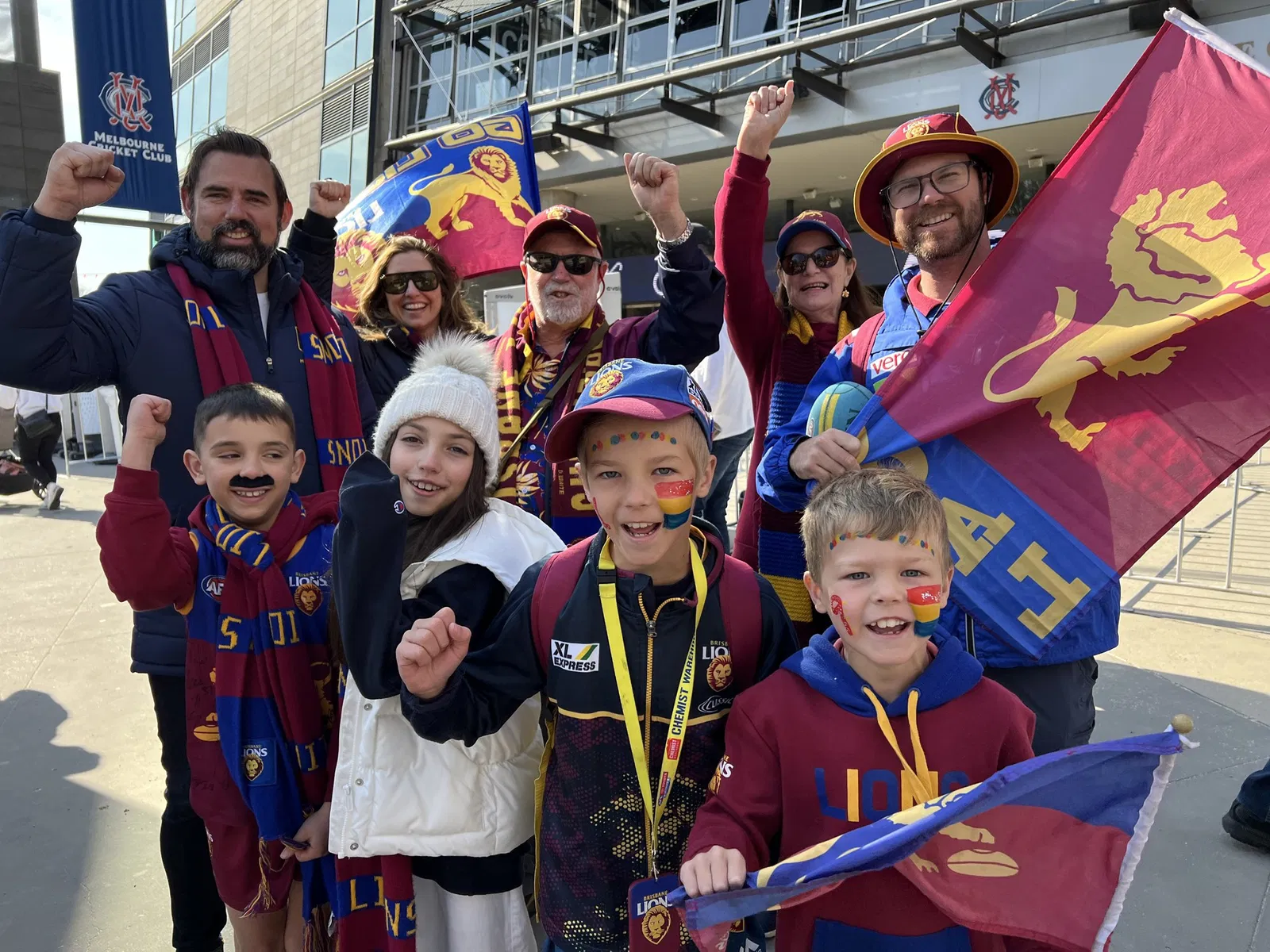 A group of adults and children dressed in Brisbane Lions attire.