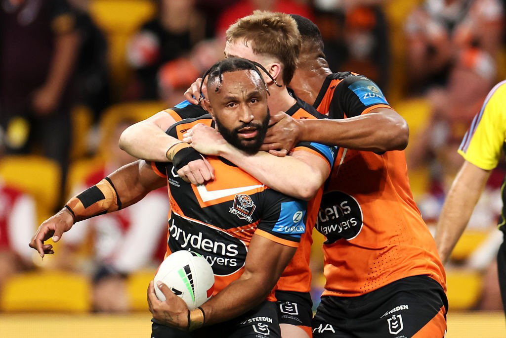Justin Olam is hugged by Wests Tigers teammates after a try in an NRL game.