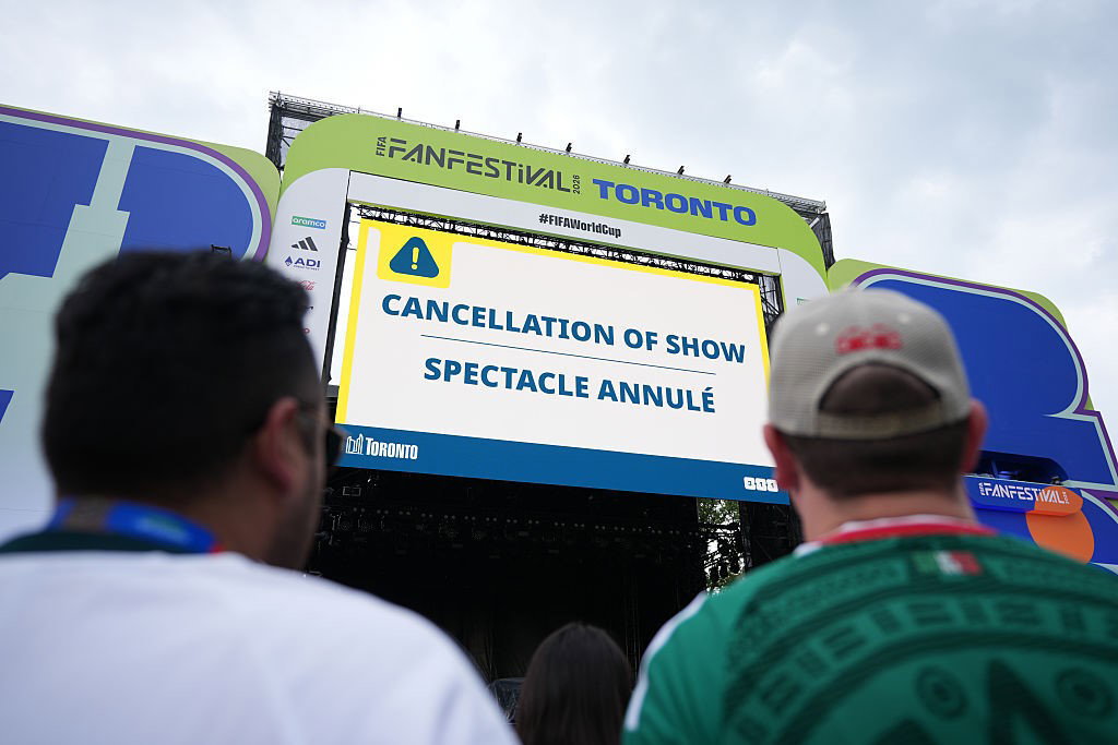 People look at a sign saying "CANCELLATION OF SHOW".