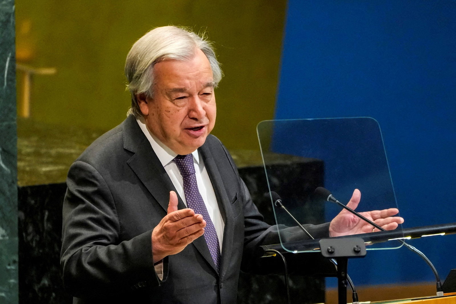 António Guterres, gestures with his hands as he speaks at a lecturn.