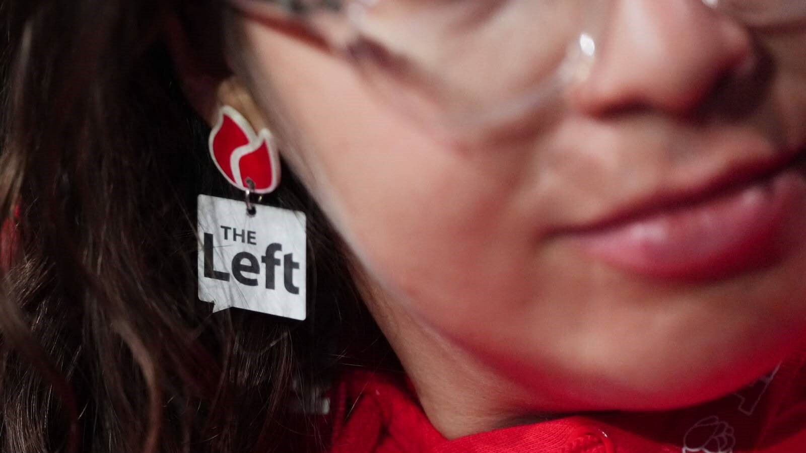 A woman wears an earing reading "The Left".