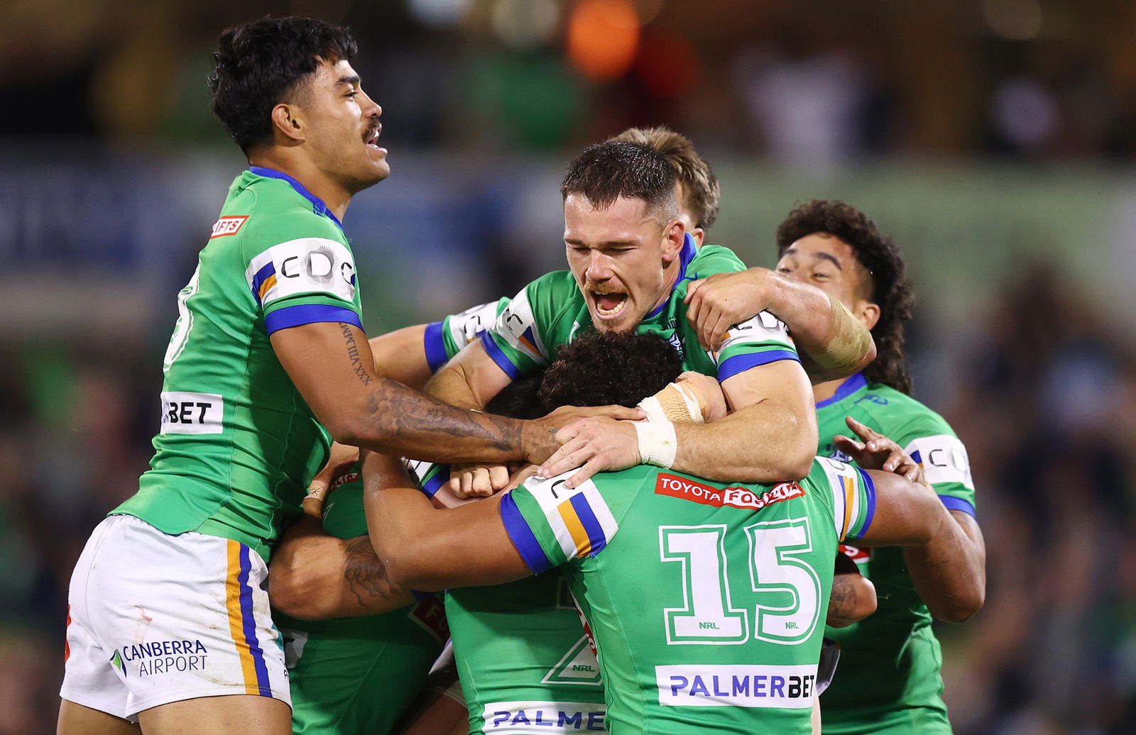 Canberra Raiders players jump on each other to celebrate during an NRL game.