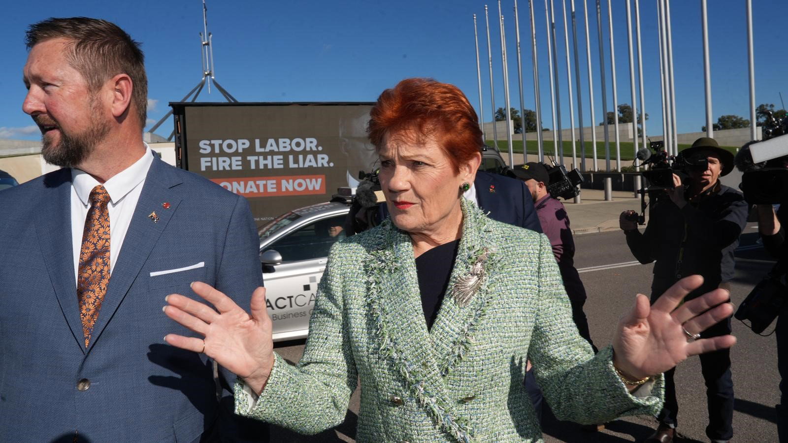 Pauline Hanson raises her hands.