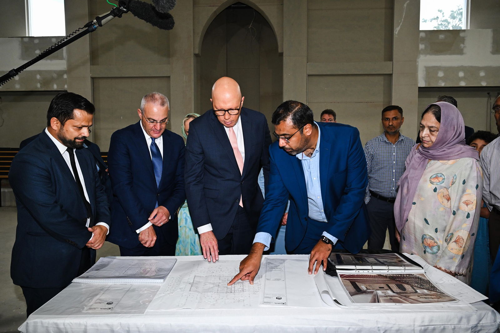 Peter Dutton looks at plans on a table inside a mosque.