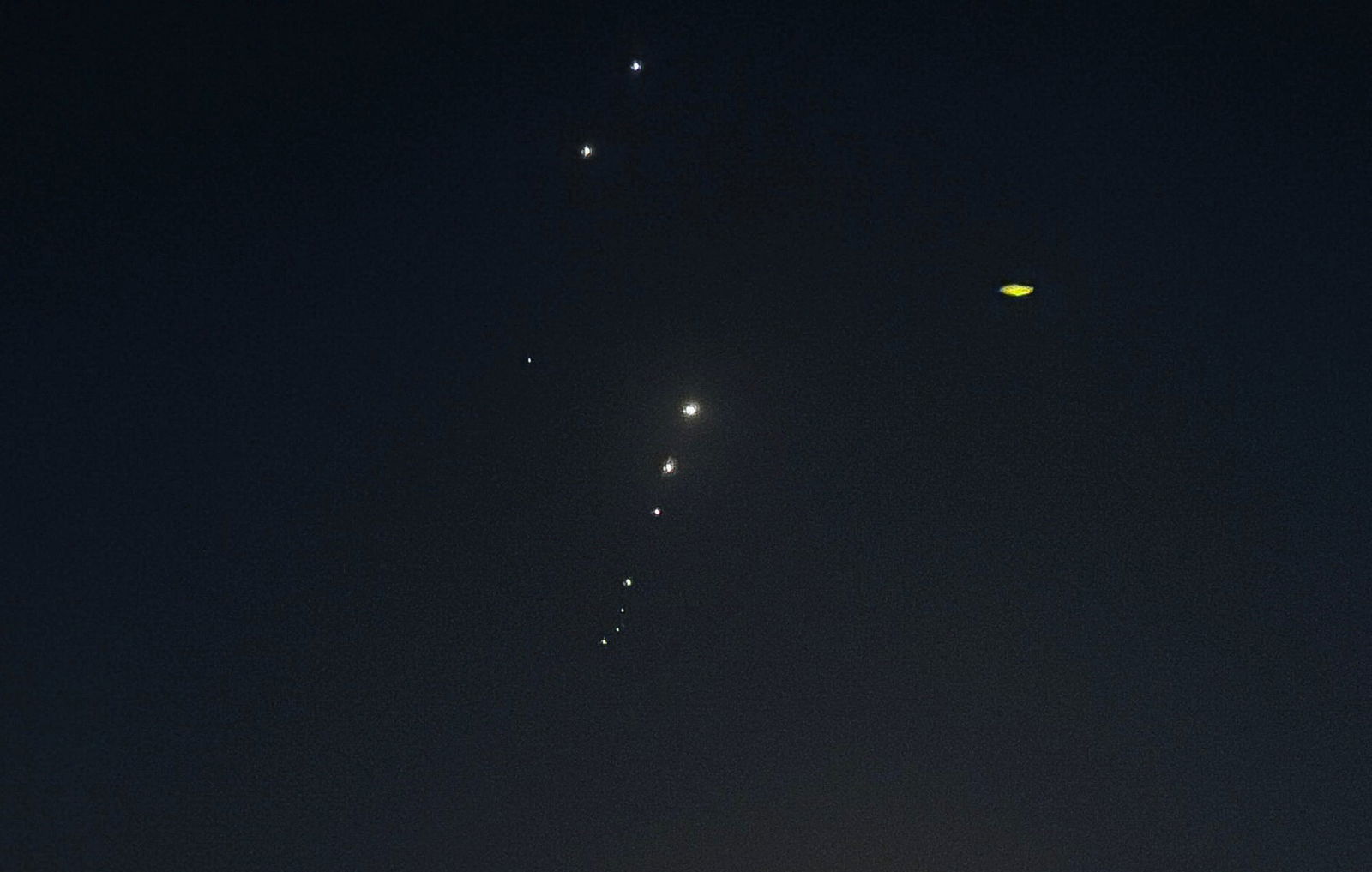 Small white dots streak through the darkened sky