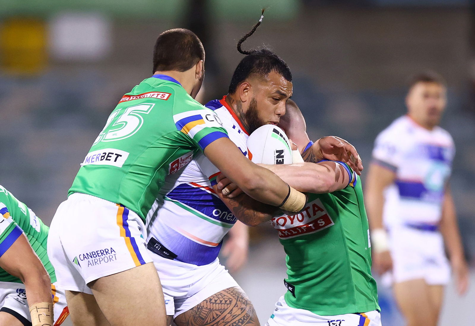 A Warriors players is tackled by two Raiders players.