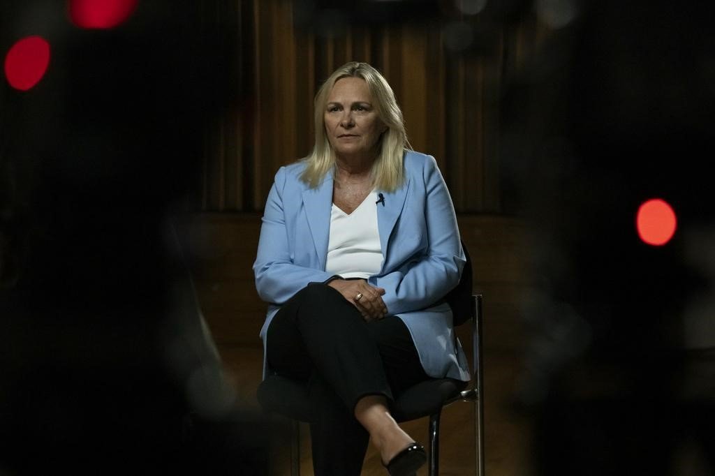 A woman with blonde hair and a powder blue jacket sits for an interview