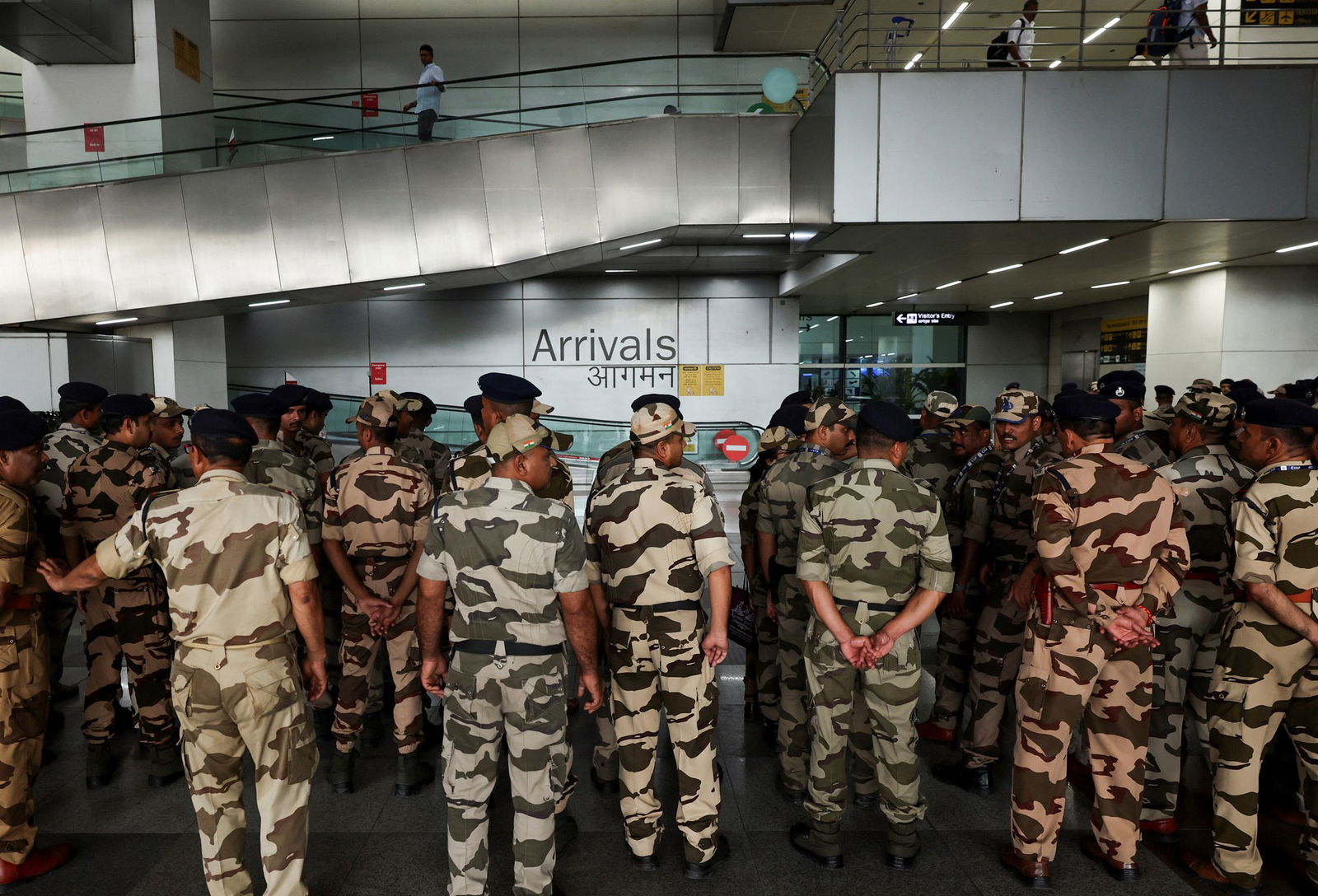 Military personnel stand next to each other in uniform in an arrivals hall at an airport