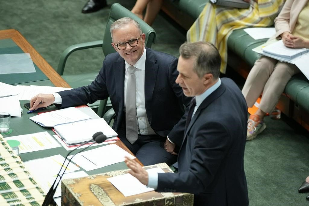 Anthony Albanese smiles as he looks at Jason Clare in the House of Representatives.