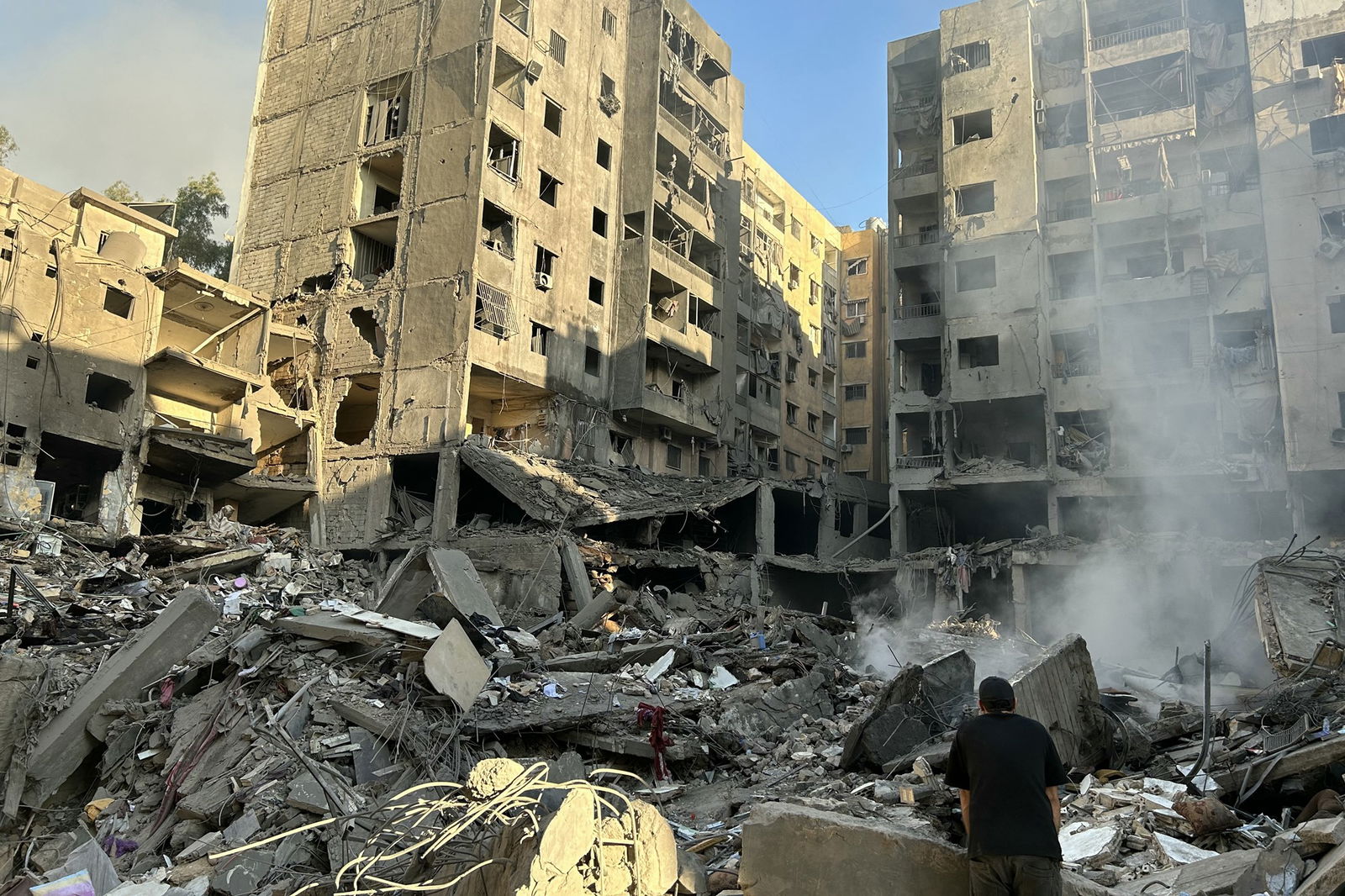 A man looks up at a building destroyed in an air strike