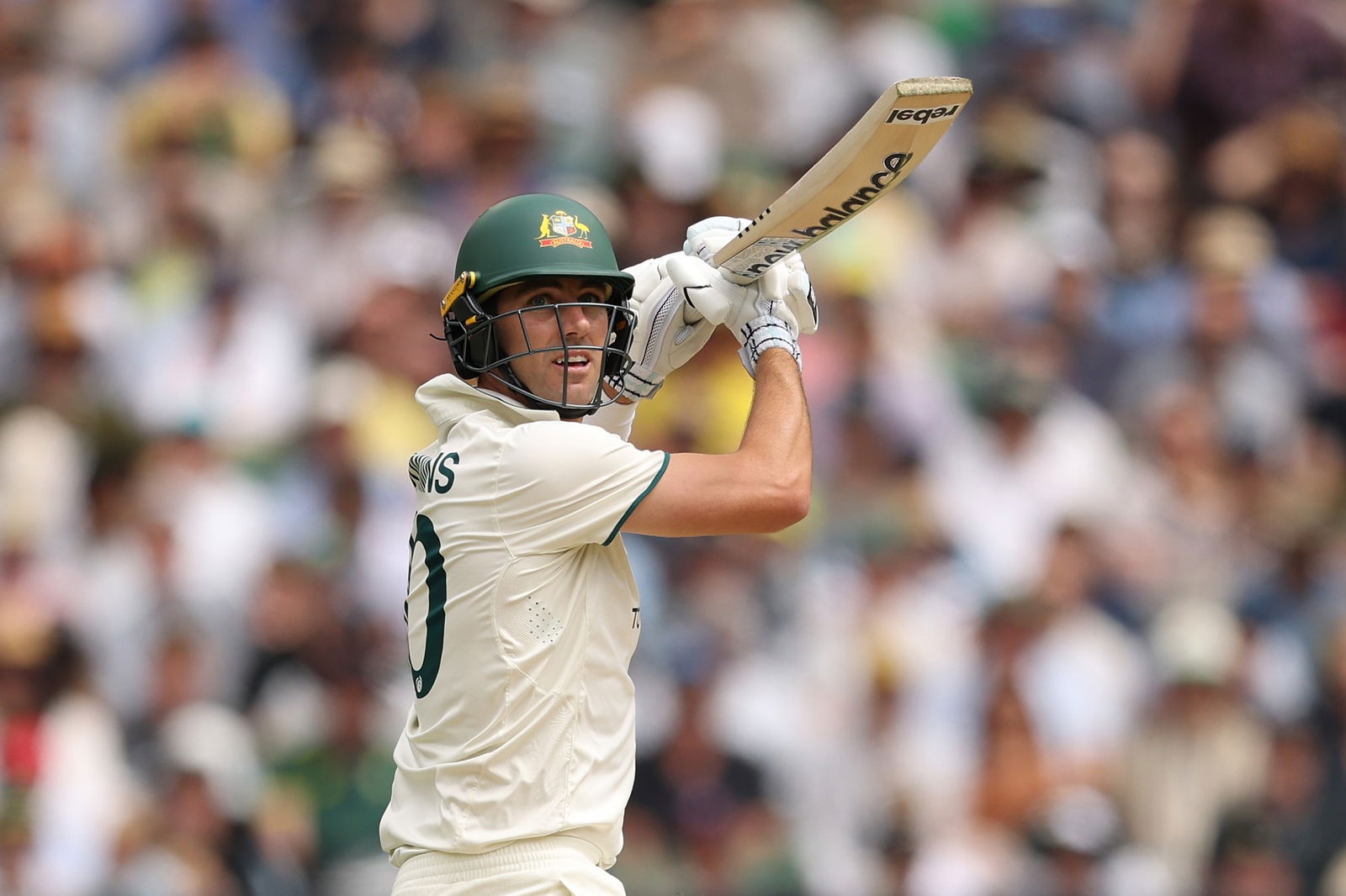 Pat Cummins looks behind himself as he completes a cricket shot.