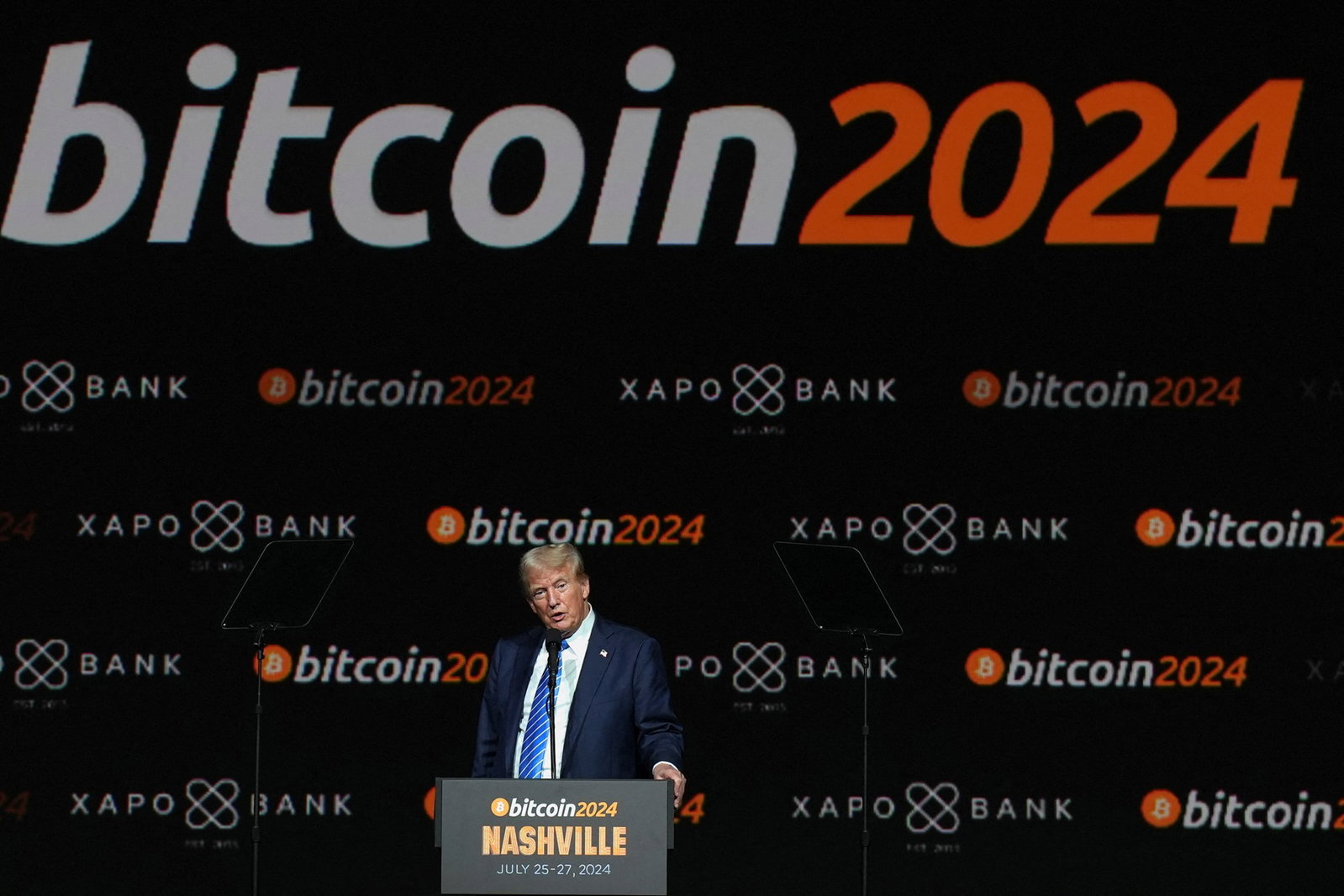 Trump at a podium with signage reading bitcoin 2024 behind him