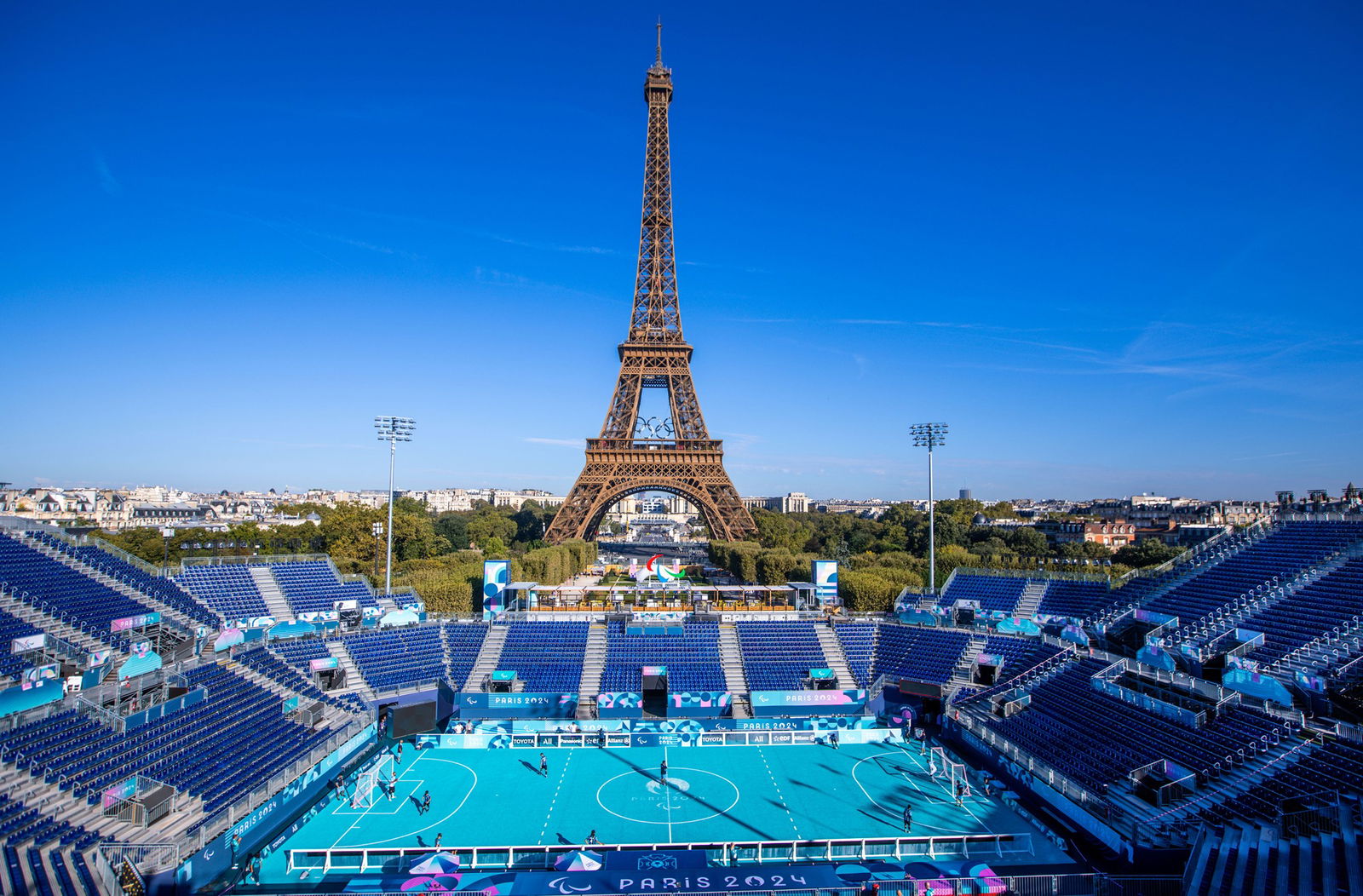 Live: Aussies Ayers and Altschwager win historic para rowing gold in Paris 7 A blue blind football field, surrounding by blue bleachers sits in front of the Eiffell Tower, which is backed by a clear blue sky and surrounded by greenery.