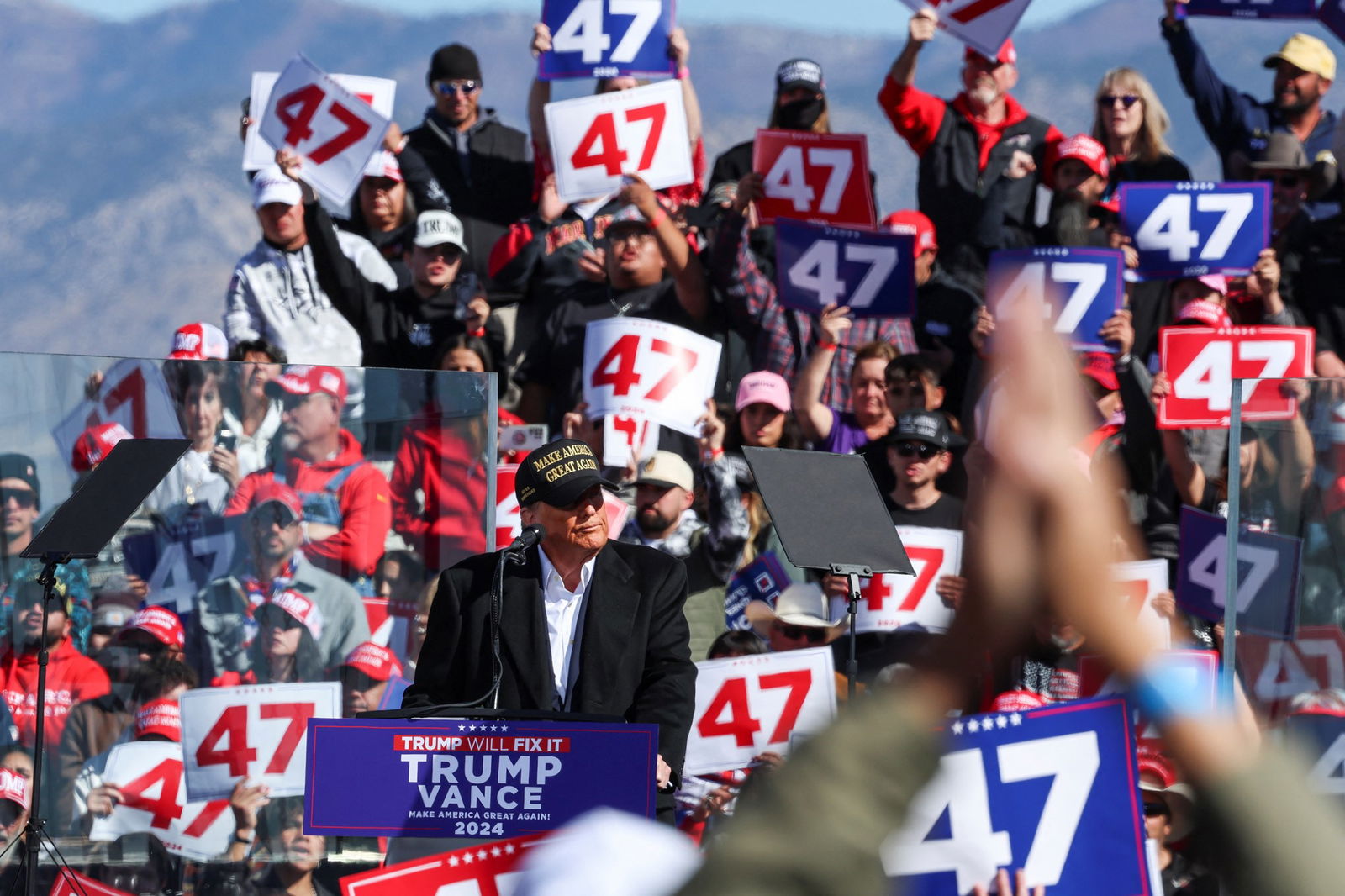 Supporters hold up signs reading 