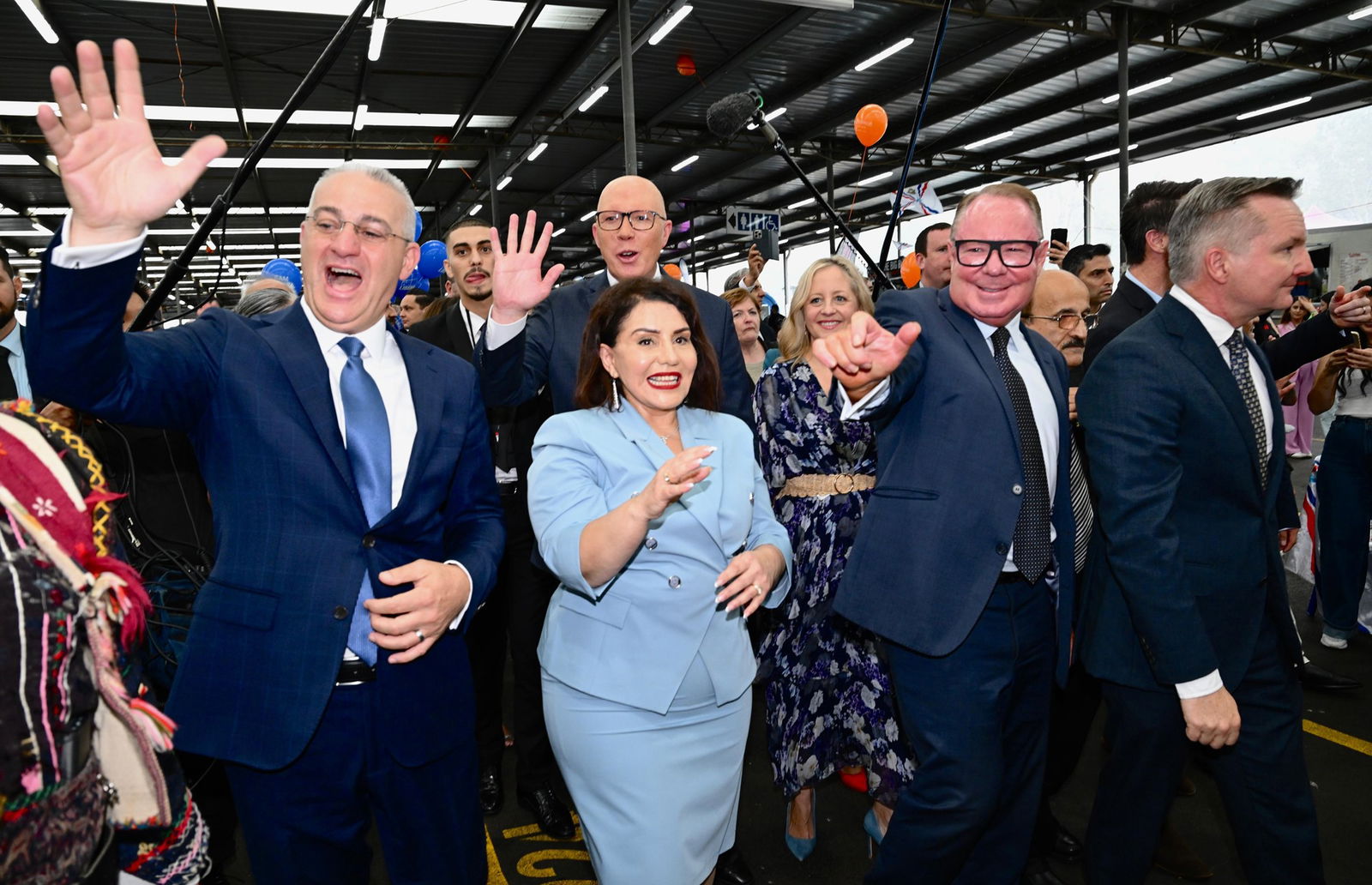 Dutton and candidates in suits wave at people in the crowd