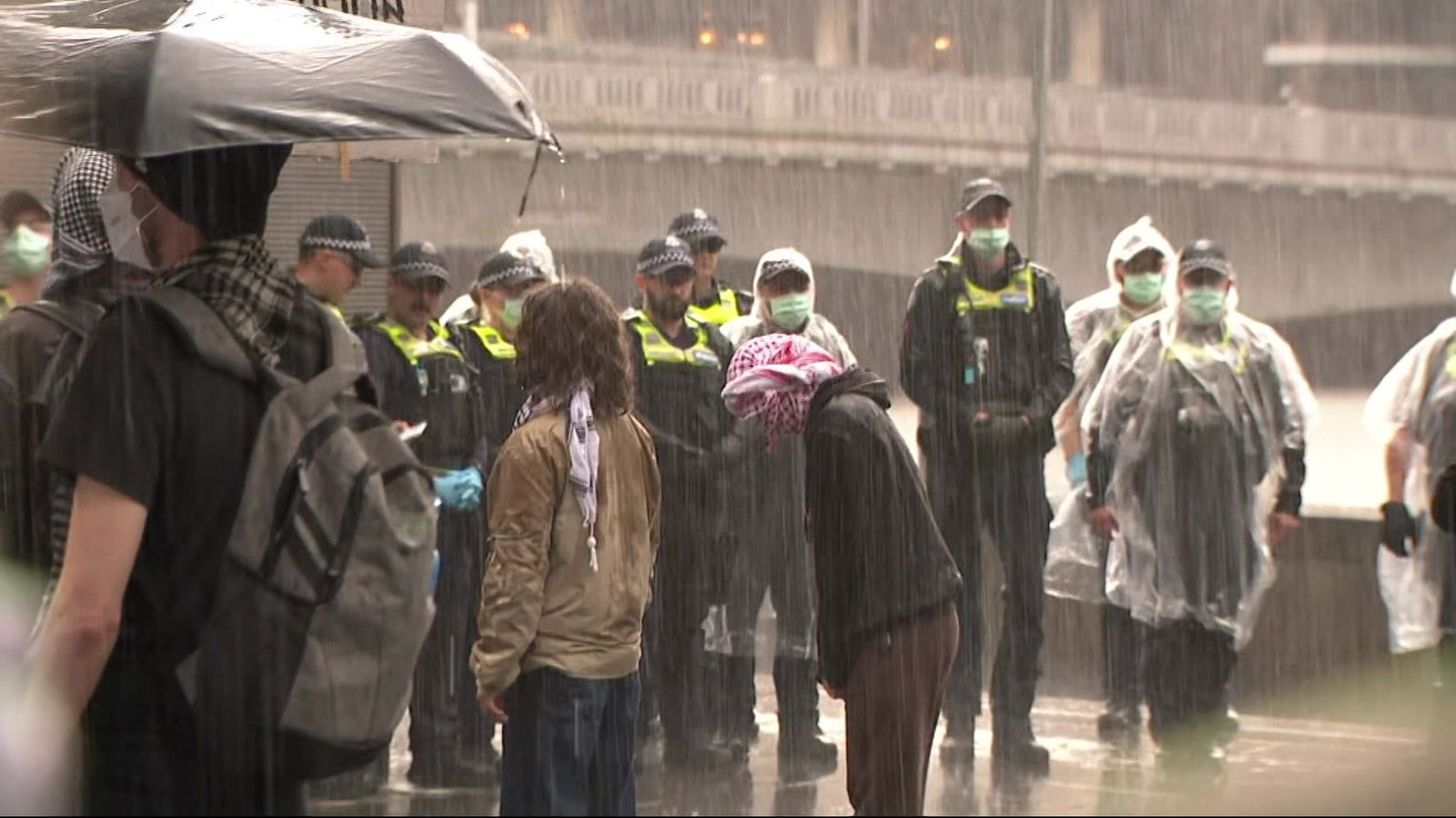 Police and protesters standing in rain