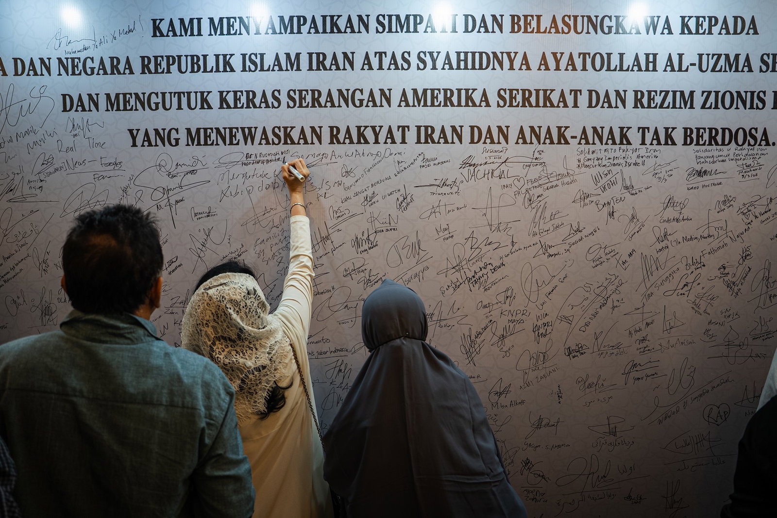 People signing their names on a wall