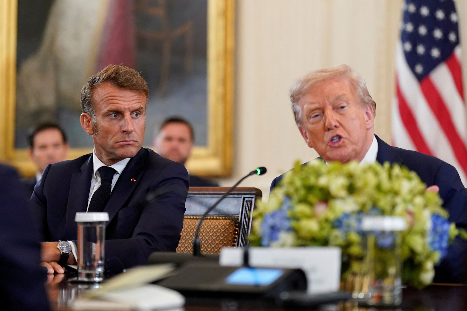 Macron watches on as Trump speaks at a large meeting table