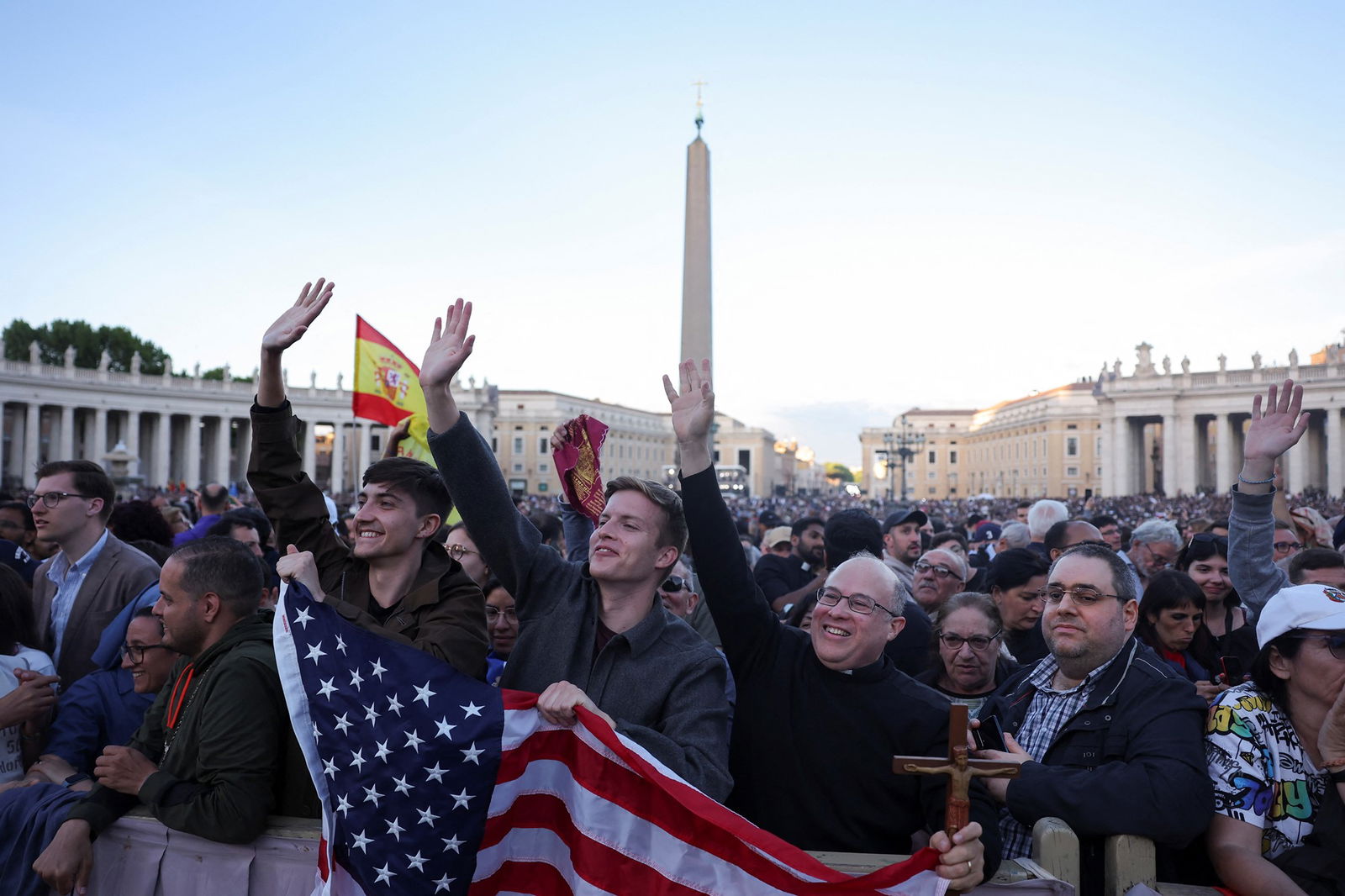 a crowd, men at the front have a US flag