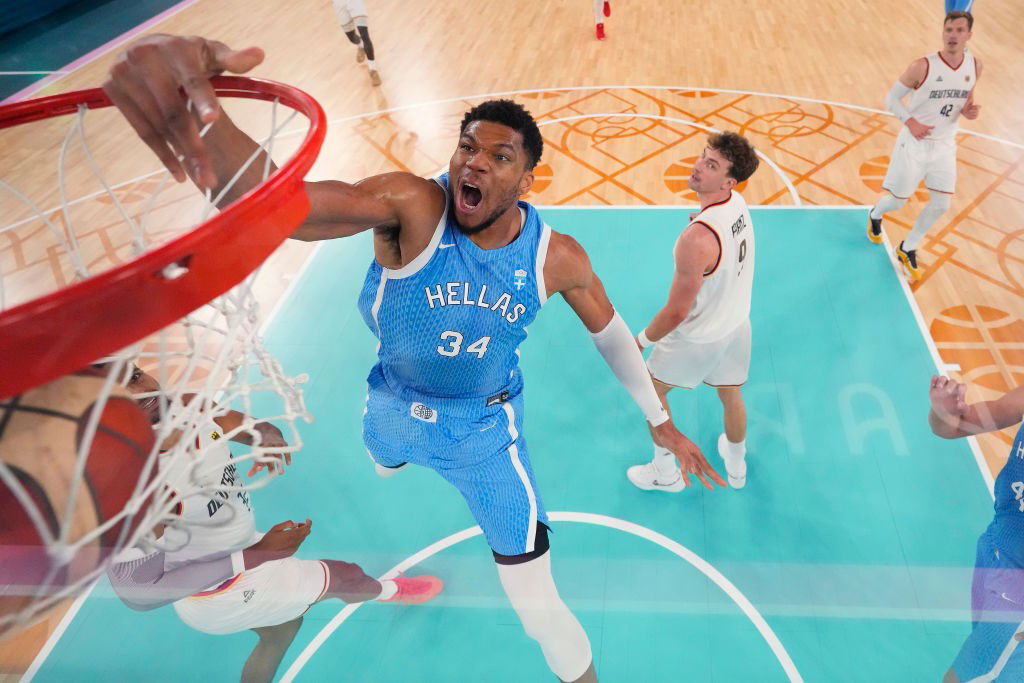 Greek Olympian Giannis Antetokounmpo  dunking a basketball against Germany on an Olympic basketball court