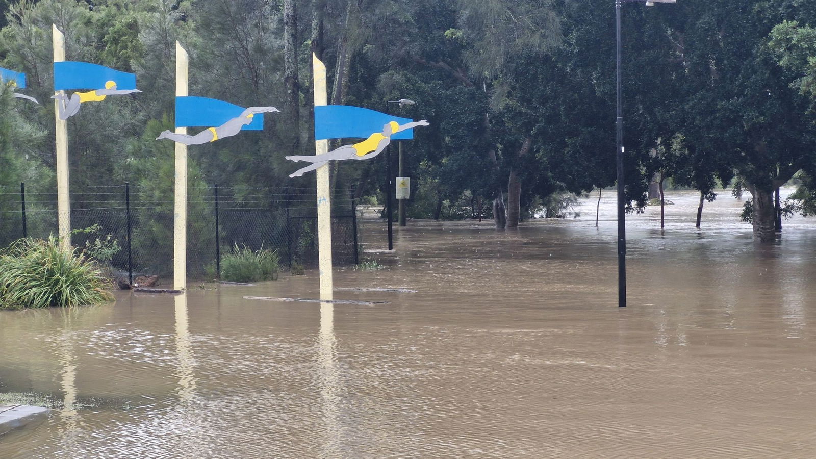 An area covered in water with three flags with people swimming on them