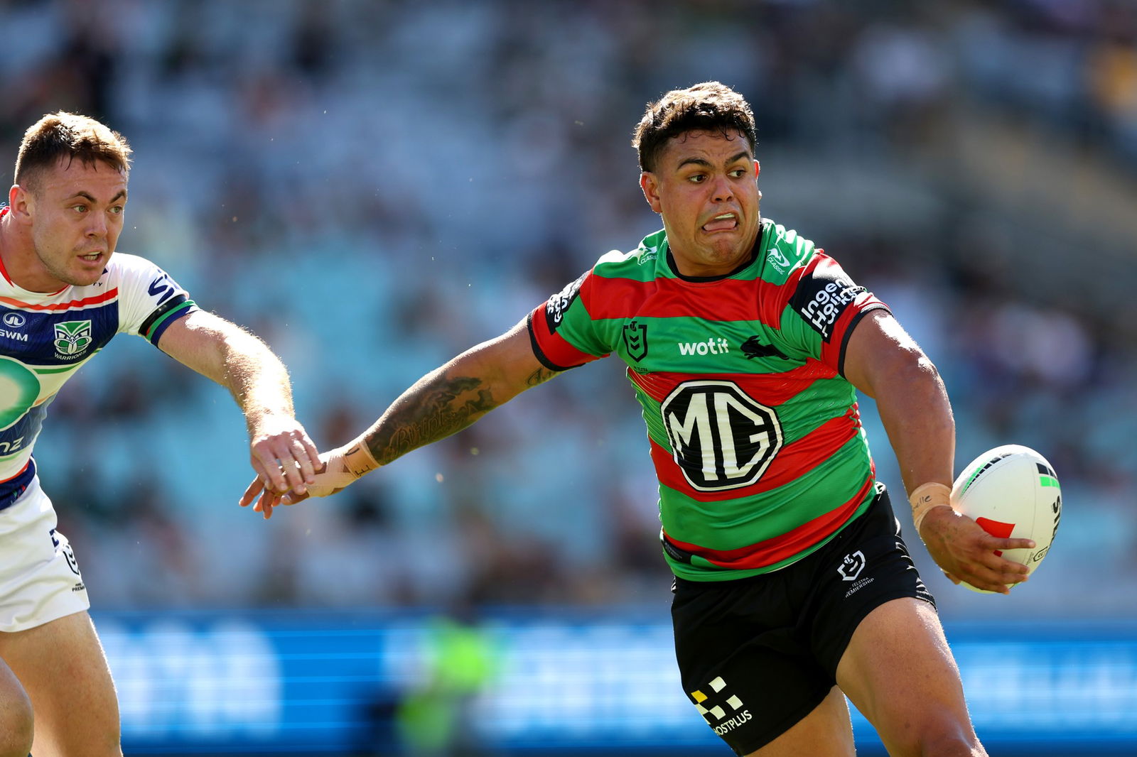 Latrell Mitchell flicks a pass during an NRL game against the Warriors.