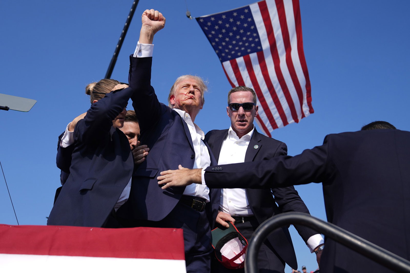 Donald Trump raises his fist in the air as he's surrounded by Secret Service agents.