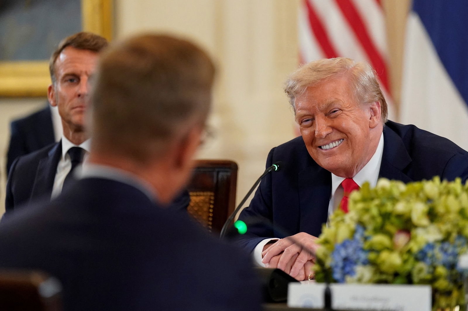 Trump grins at a man across the table from him