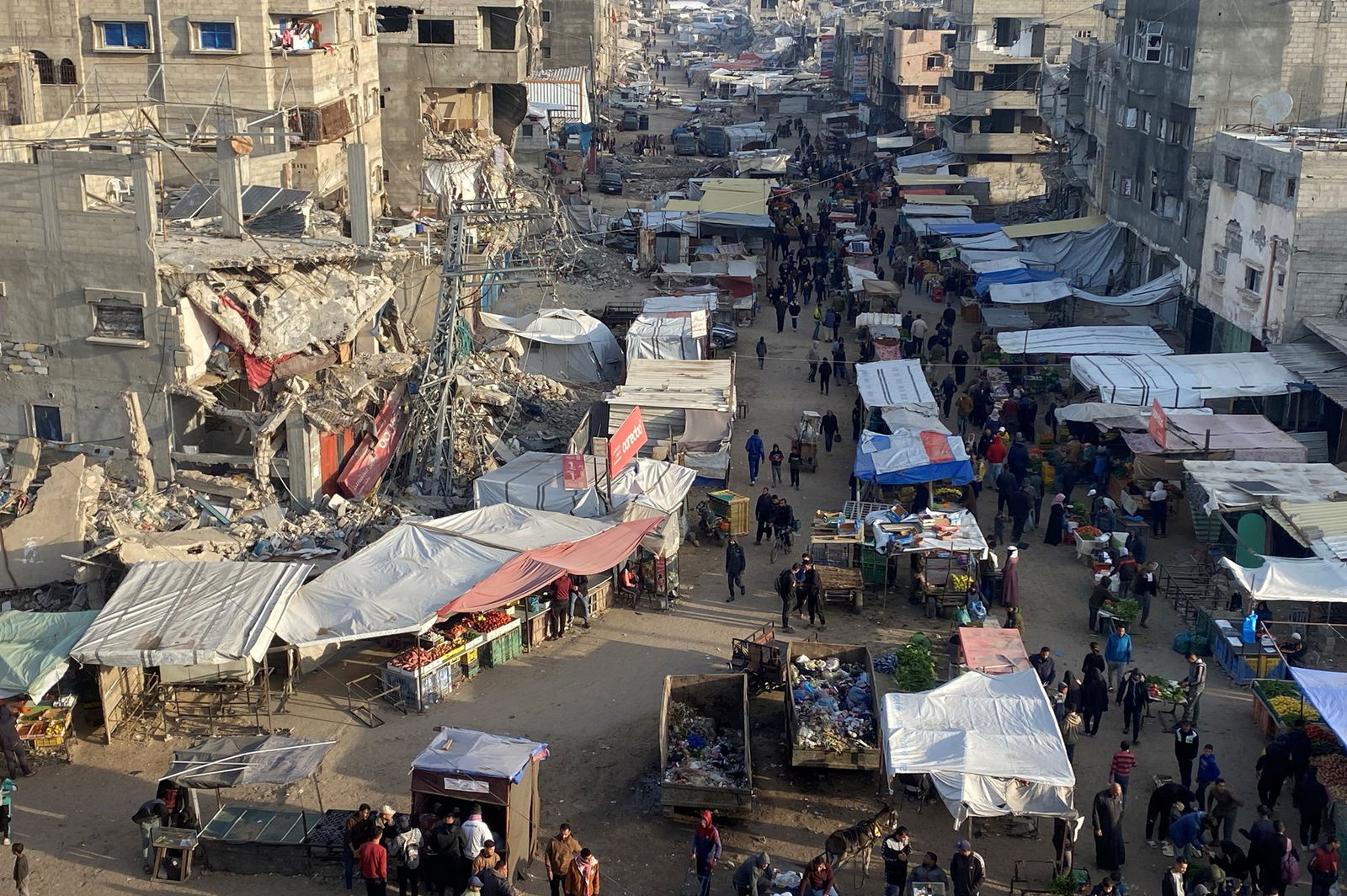 An aerial shot of a market place next to building rubble 