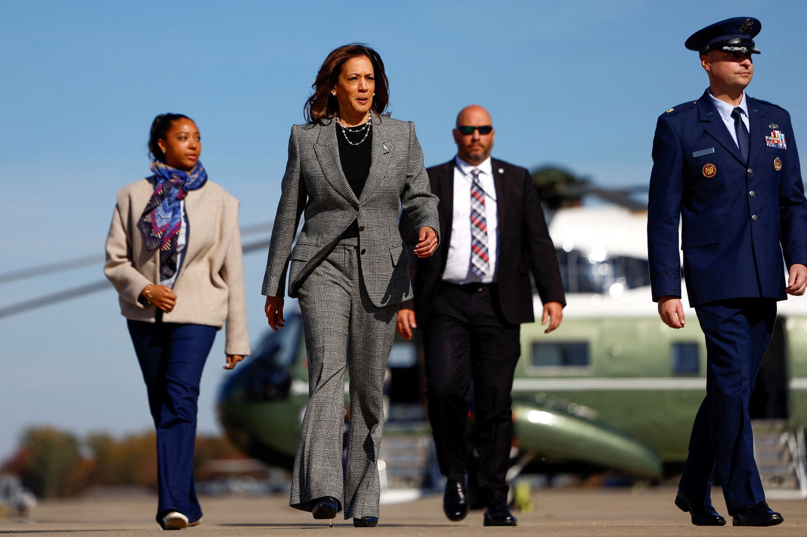 Kamala Harris walks on the asphalt with workers on either side