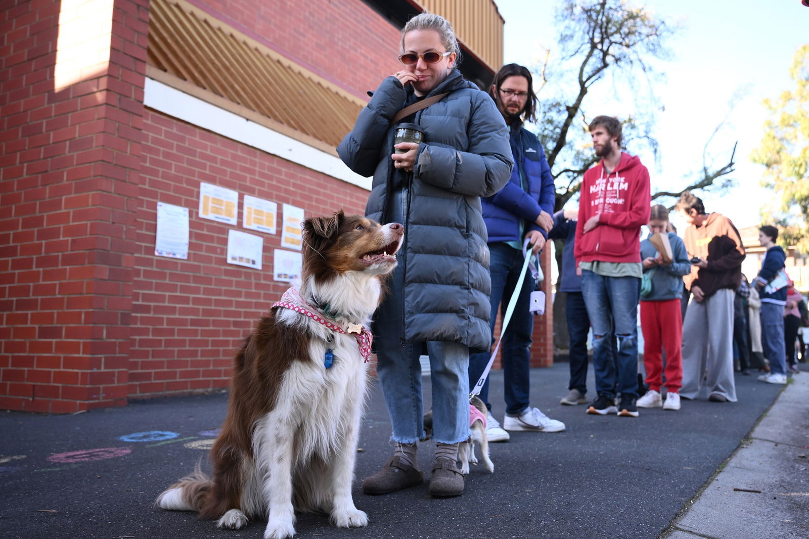 A woman in a black puffer jacket standing alongside a border collie