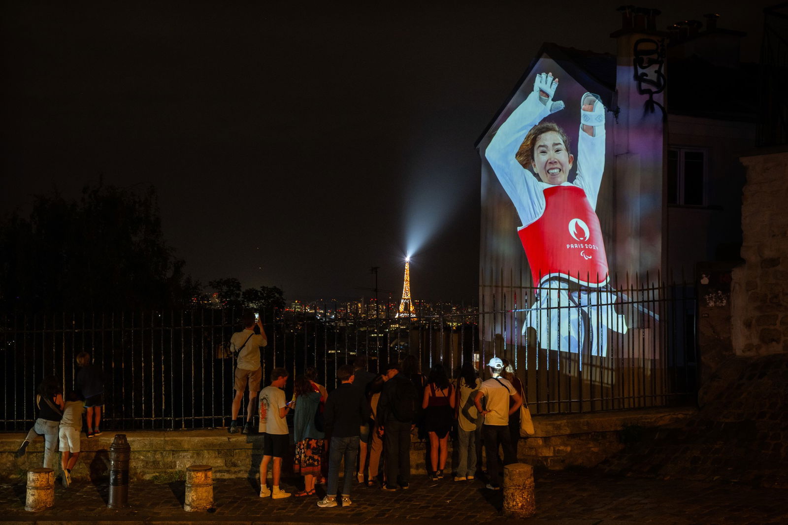 An image of Zakia Khudadadi of the Refugee Paralympic Team is projected on the Paris skyline, with the Eiffel Tower in the background. 