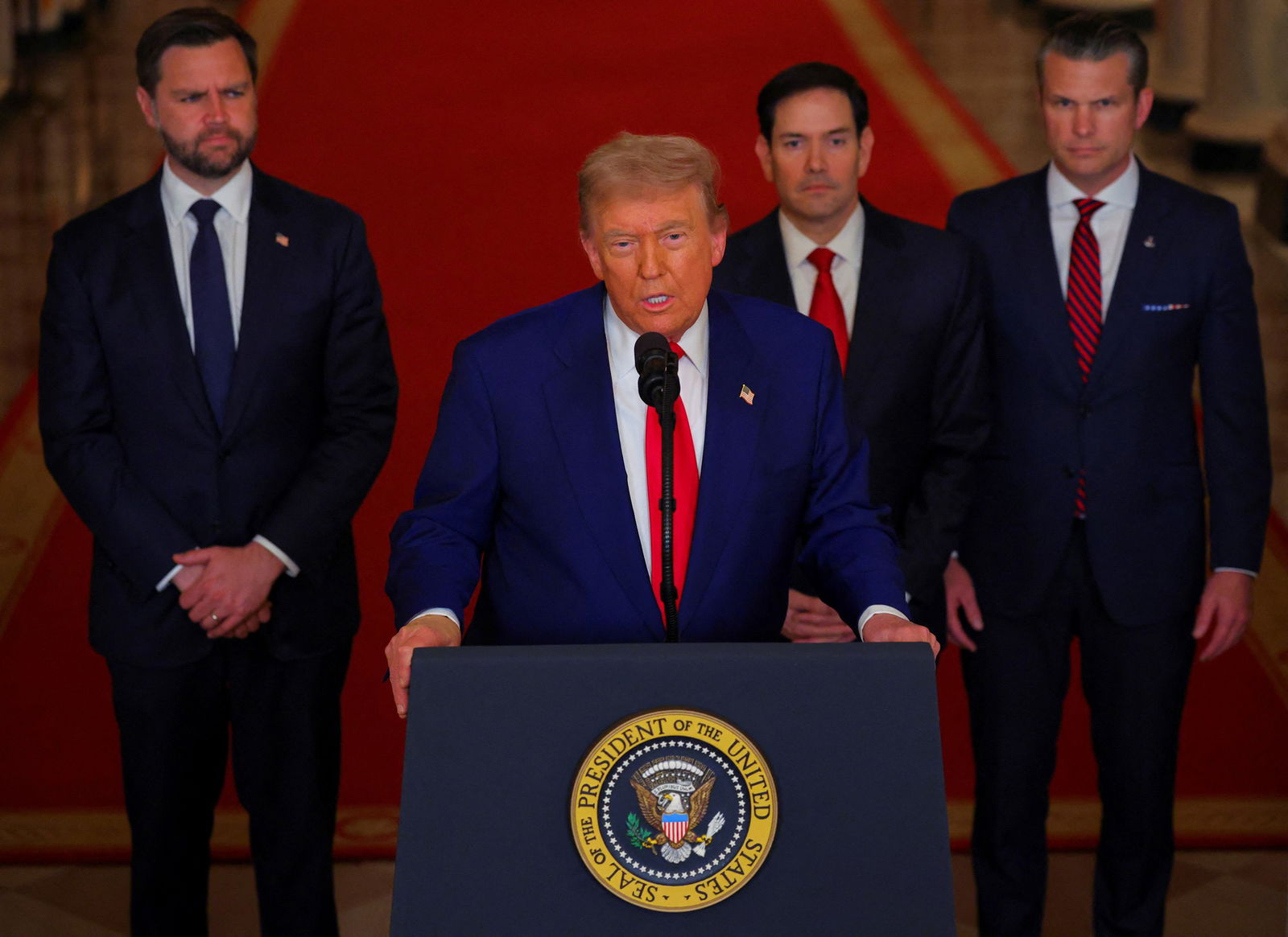 Donald Trump at the White House podium, with JD Vance, Marco Rubio and Pete Hegseth behind him.
