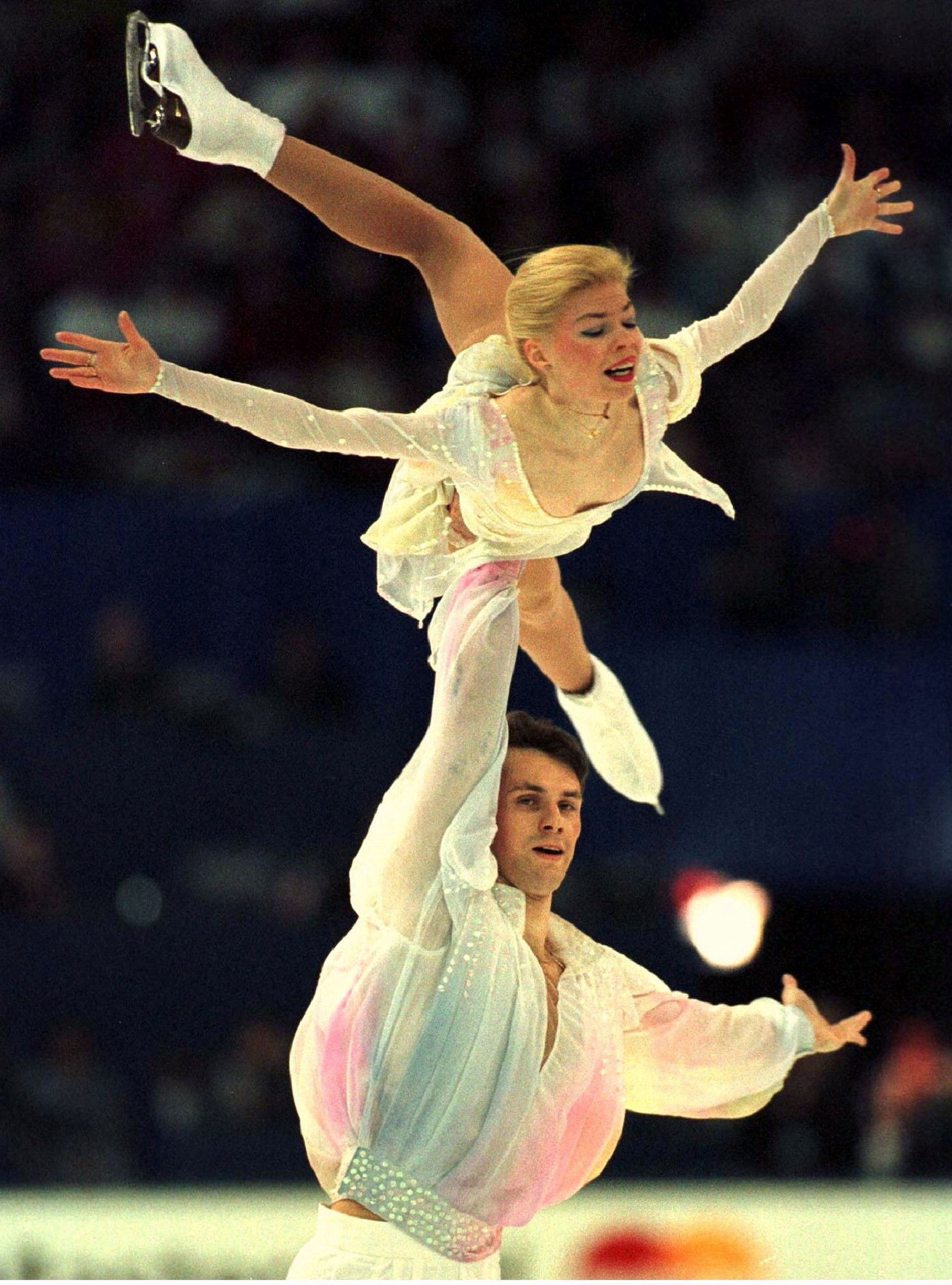 A male figure skater holding up a woman. 